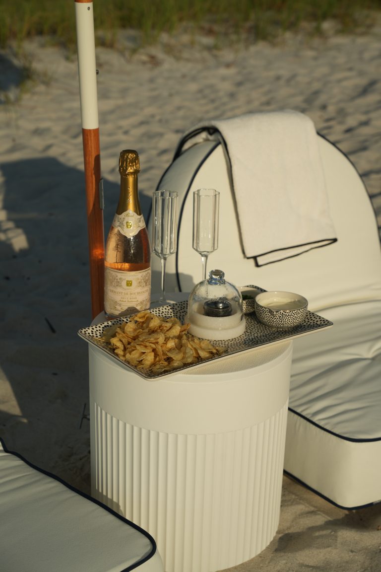 Chilled glasses and a styled tray on a beach table