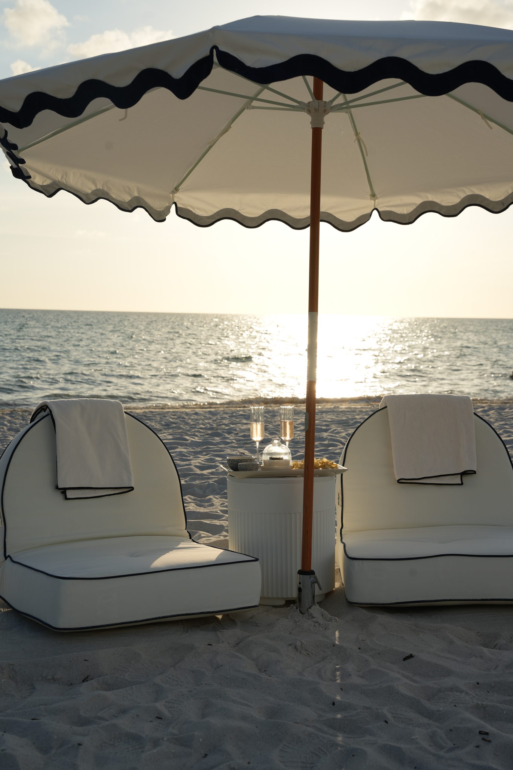 A styled beach setup with real shade waiting on the sand before guests arrive